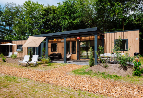 Moderne Cottage Next XXL Family Deluxe lodge på Papillon Country Resort, omgivet af grønne træer og terrasser.