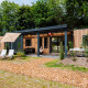 Moderne Cottage Next XXL Family Deluxe lodge på Papillon Country Resort, omgivet af grønne træer og terrasser.