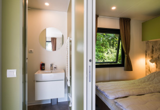 Moderne lodge met slaapkamer en badkamer, grote ramen in Papillon Country Resort, Nederland.