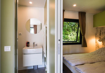 Cabaña moderna con dormitorio, baño y ventanales en Cottage Next XXL Family Deluxe, Papillon Country Resort, Países Bajos.