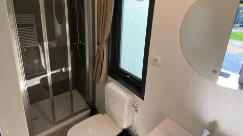 Moderne badkamer met douche, toilet, raam en spiegel in Cottage Next XXL Family Deluxe in Nederland.