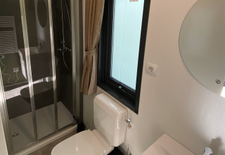 Salle de bain moderne avec cabine de douche, toilettes, fenêtre et miroir au Cottage Next XXL Family Deluxe aux Pays-Bas.
