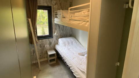 Kleine slaapkamer met stapelbed, raam en nachtkastje in Cottage Next XXL Family Deluxe, Papillon Country Resort.