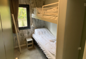 Small bedroom with bunk beds, window, and nightstand at Cottage Next XXL Family Deluxe, Papillon Country Resort.