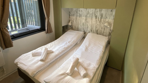 Schlafzimmer im Cottage Next XXL Family Deluxe im Papillon Country Resort mit zwei Einzelbetten und Fenster.