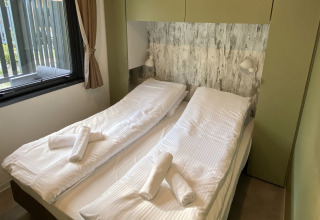 Camera da letto nel Cottage Next XXL Family Deluxe al Papillon Country Resort con due letti singoli e finestra.