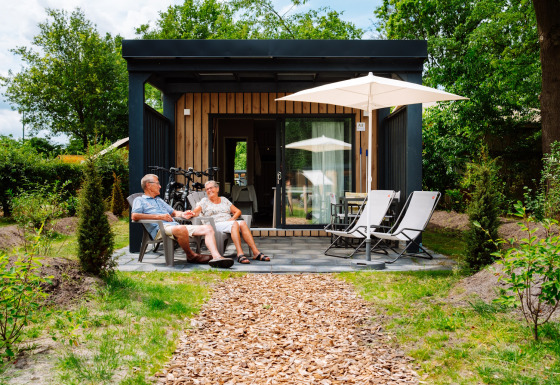 Ældre par nyder afslapning på terrassen foran Cottage Suite, Papillon Country Resort, Nederlandene.