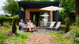 Älteres Paar entspannt sich auf der Terrasse des Cottage Suite im Papillon Country Resort, Niederlande.