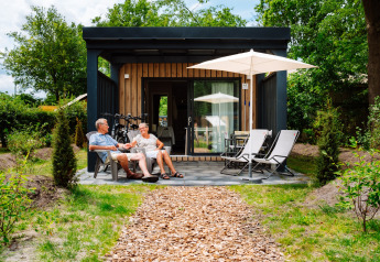 Oud koppel ontspant op het terras van de Cottage Suite in Papillon Country Resort, Nederland.