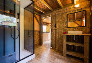 Baño rústico con ducha de cristal y detalles de madera en Air Dreamer 3 Deluxe, Papillon Country Resort.