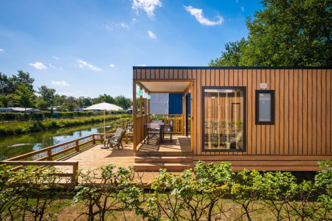 Fish Cabin Deluxe lodge aan het meer bij Papillon Country Resort, Nederland, met ruime houten veranda.