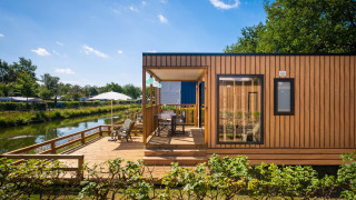 Fish Cabin Deluxe lodge aan het meer bij Papillon Country Resort, Nederland, met ruime houten veranda.
