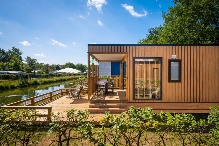 Modern Fish Cabin Deluxe lodge by the lake at Papillon Country Resort, Netherlands, with a spacious deck.
