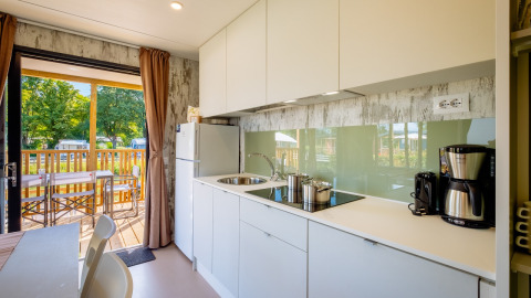 Cocina moderna con muebles blancos en Fish Cabin Deluxe de Papillon Country Resort, Países Bajos, vista a terraza.