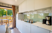 Cocina moderna con muebles blancos en Fish Cabin Deluxe de Papillon Country Resort, Países Bajos, vista a terraza.