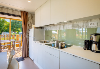 Cocina moderna con muebles blancos en Fish Cabin Deluxe de Papillon Country Resort, Países Bajos, vista a terraza.