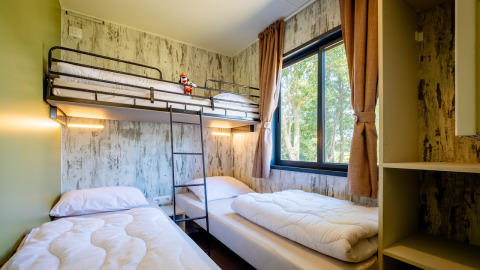 Kamer in Fish Cabin Deluxe van Papillon Country Resort met stapelbed, twee losse bedden en groot raam.