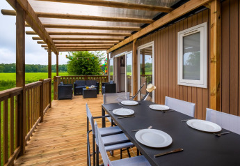 Houten terras met eettafel en loungehoek aan Cottage Next XL, Papillon Country Resort, Nederland.