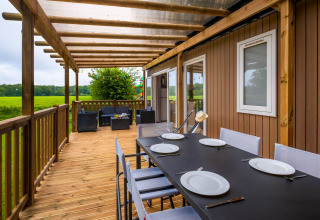 Træterrasse med spisebord og loungeområde ved Cottage Next XL, Papillon Country Resort, Nederlandene.