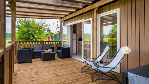 Træterrasse ved Cottage Next XL på Papillon Country Resort i Holland, med loungemøbler og lænestole.