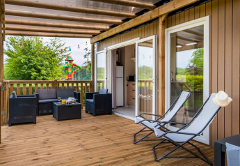 Træterrasse ved Cottage Next XL på Papillon Country Resort i Holland, med loungemøbler og lænestole.