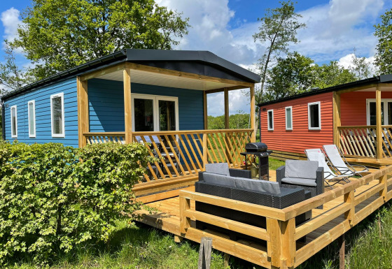 Buitenterras aan Fish Cabin lodge, Papillon Country Resort, Nederland, met blauwe en rode huisjes.