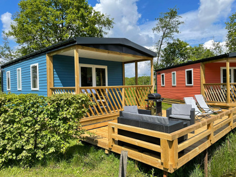Außenterrasse der Fish Cabin Lodge im Papillon Country Resort, Niederlande, mit blauen und roten Hütten.