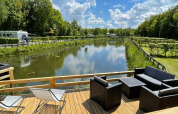 Gezicht vanaf Fish Cabin bij Papillon Country Resort in Nederland, terras naast een kanaal en veel groen.