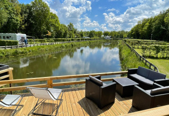 Vista dalla Fish Cabin al Papillon Country Resort nei Paesi Bassi, terrazza sul canale e verde lussureggiante.