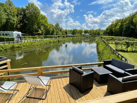 Vista dalla Fish Cabin al Papillon Country Resort nei Paesi Bassi, terrazza sul canale e verde lussureggiante.