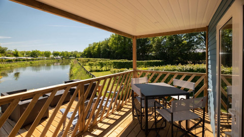 Zicht vanaf de Fish Cabin in Papillon Country Resort in Nederland, met terras, stoelen en kanaaltje.