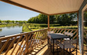 Zicht vanaf de Fish Cabin in Papillon Country Resort in Nederland, met terras, stoelen en kanaaltje.