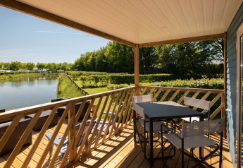 Vista dalla Fish Cabin al Papillon Country Resort nei Paesi Bassi con terrazza, sedie e canale.