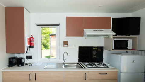 Moderne Küchenzeile in der Fish Cabin im Papillon Country Resort, mit Herd, Mikrowelle und Kühlschrank.