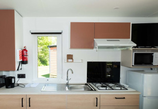 Moderne Küchenzeile in der Fish Cabin im Papillon Country Resort, mit Herd, Mikrowelle und Kühlschrank.