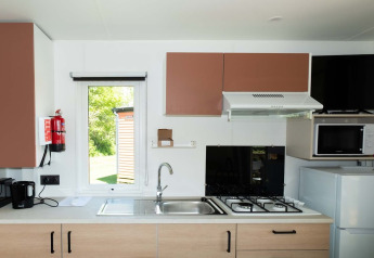 Moderne kitchenette in Fish Cabin bij Papillon Country Resort, Nederland, met kookplaat, magnetron en koelkast.