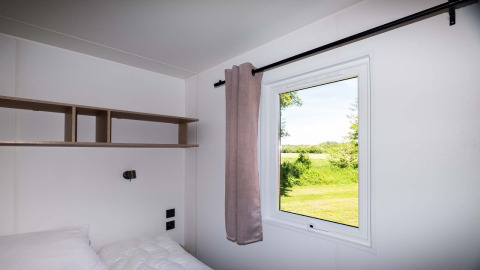 Dormitorio moderno en Fish Cabin en Papillon Country Resort con ventana y vista a la naturaleza verde.