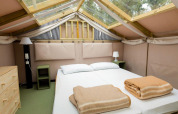 Slaapkamer in Air Lodge 2.0 van Papillon Country Resort met tweepersoonsbed, nachtkastjes en dakraam.