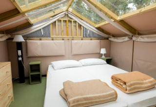 Soveværelse i Air Lodge 2.0 på Papillon Country Resort, med dobbeltseng, sengeborde og ovenlysvindue.