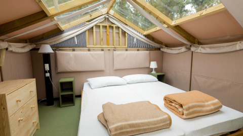 Slaapkamer in Air Lodge 2.0 van Papillon Country Resort met tweepersoonsbed, nachtkastjes en dakraam.