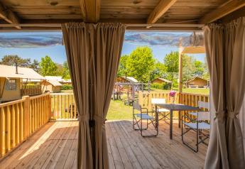 Terraza de madera con mesa y sillas en Air Lodge 2.0 del Papillon Country Resort, Países Bajos, día soleado.