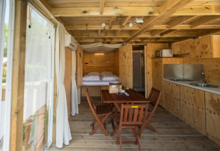 Binnenzicht van Air Lodge 2.0 op Papillon Country Resort, met houten interieur en gezellige eethoek.