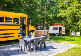 Vista esterna del lodge Schoolbus Papillon e roulotte con area salotto al Papillon Country Resort.