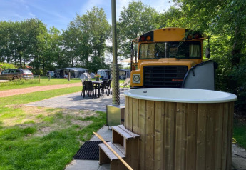 Udendørs scene ved Schoolbus Papillon, Papillon Country Resort, med skolebus, spisebord og vildmarksbad.