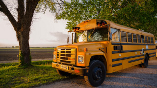 Autobús escolar amarillo aparcado al atardecer junto a un árbol en la posada Schoolbus Papillon.