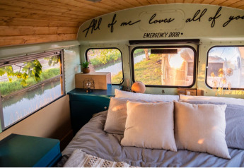 Accogliente camera da letto in uno scuolabus al Schoolbus Papillon, Papillon Country Resort nei Paesi Bassi.