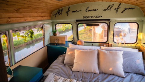 Accogliente camera da letto in uno scuolabus al Schoolbus Papillon, Papillon Country Resort nei Paesi Bassi.