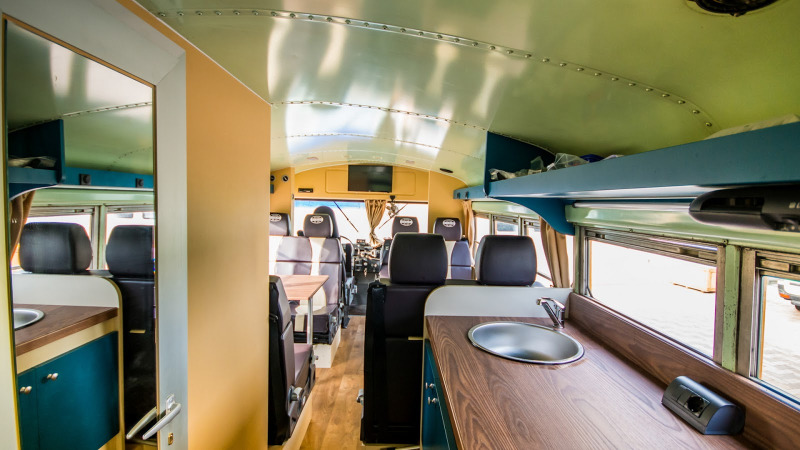 Interior of Schoolbus Papillon lodge at Papillon Country Resort in the Netherlands, with kitchen and seating.