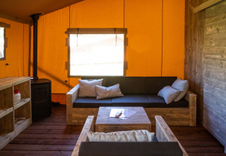 Binnenzicht van de Safarilodge Deluxe bij Papillon Country Resort, met houten meubels en oranje wanden.