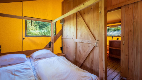 Vista interior de una cabaña de madera con cama doble en Safarilodge Deluxe, Papillon Country Resort, Países Bajos.